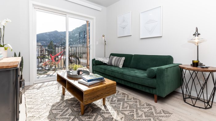 a living room with a green couch and a view of mountains at The Bighorn Crossing