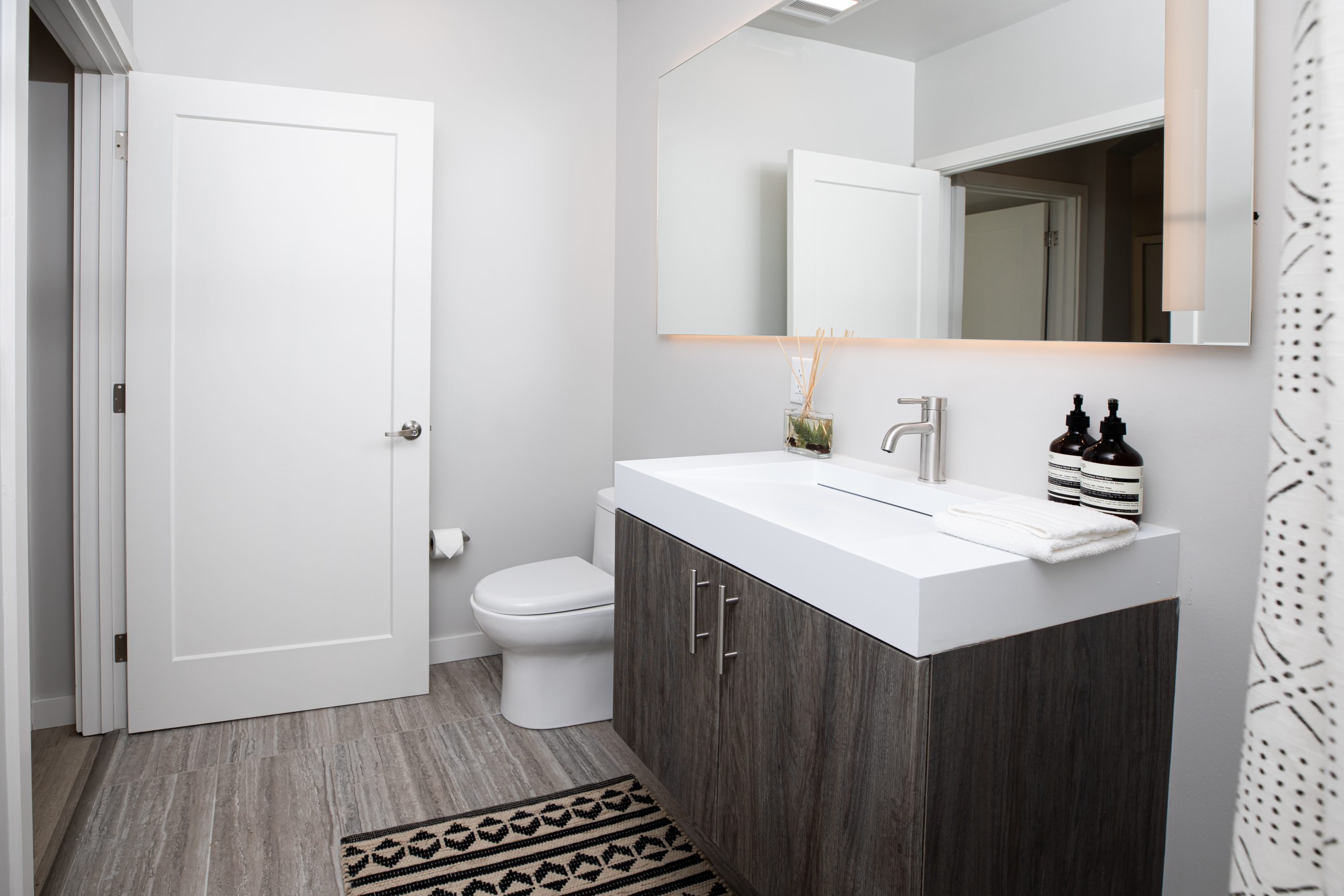 a bathroom with a white vanity and wooden floor at The Bighorn Crossing